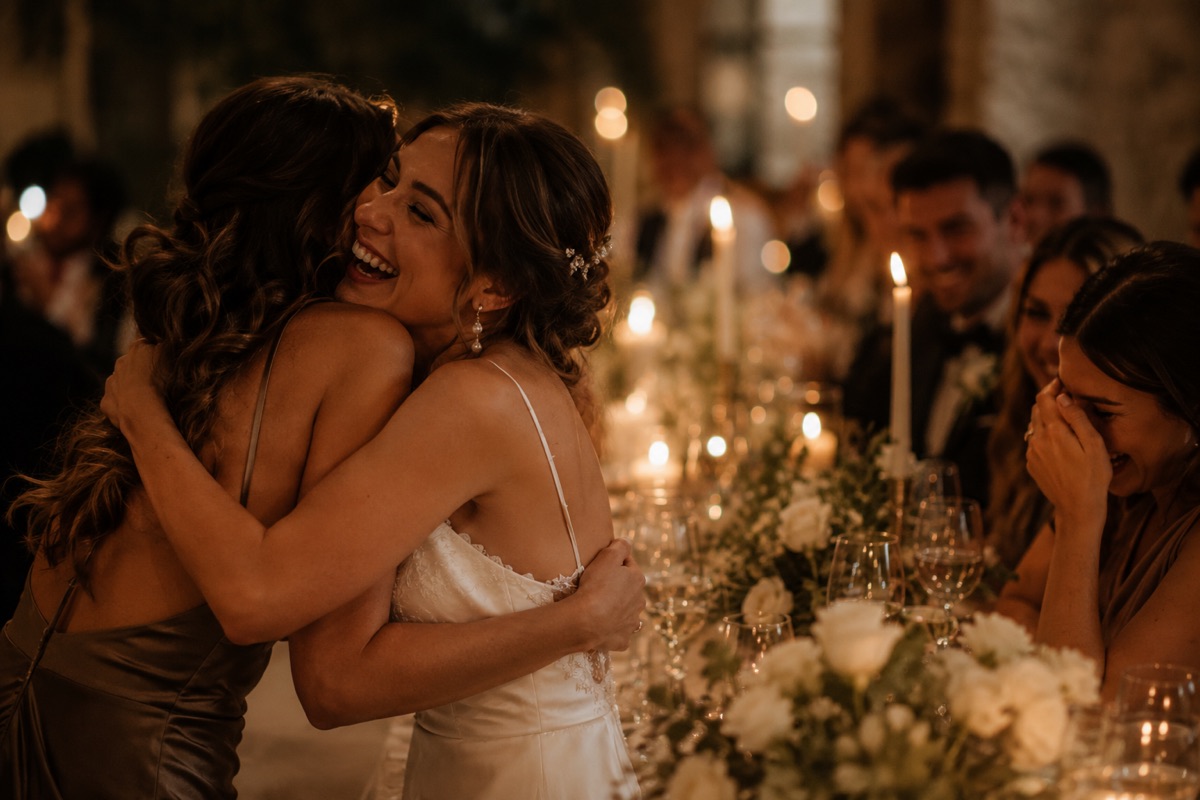 Bride laughing with a guest at a candle-lit wedding reception